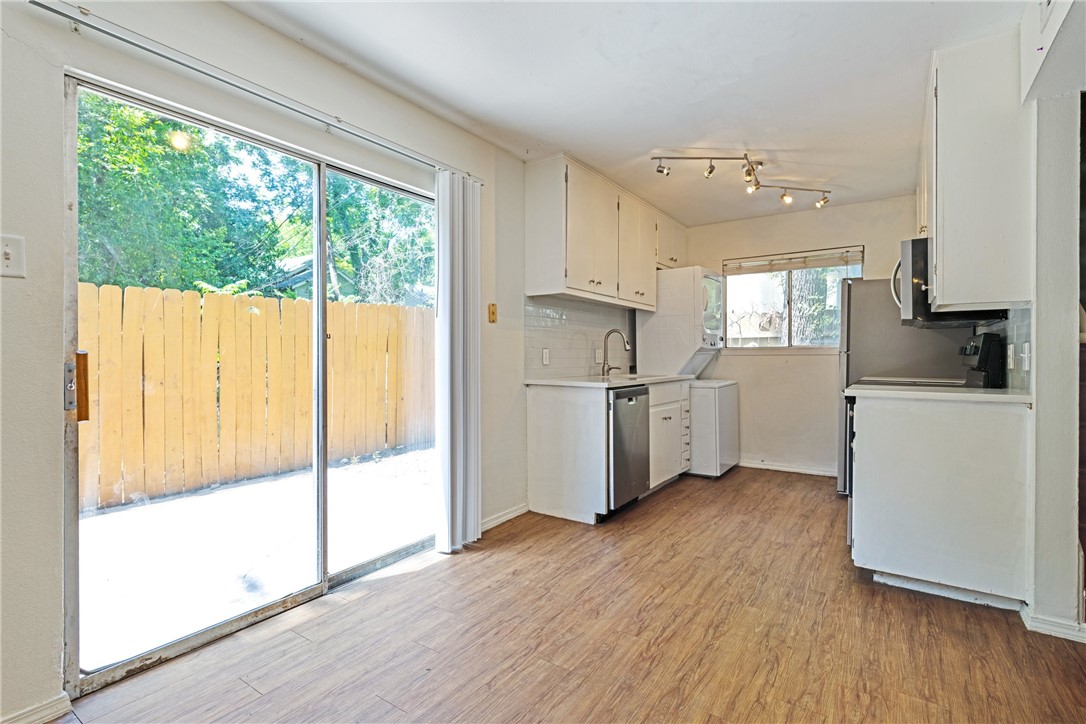 607 East 43rd Street, Unit A Austin, TX 78751 - Photo 18 of 26 a kitchen with stainless steel appliances a refrigerator a sink and white cabinets with wooden floor