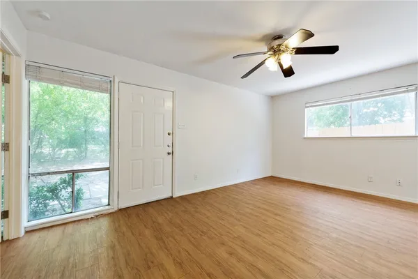 a view of an empty room with wooden floor and a window