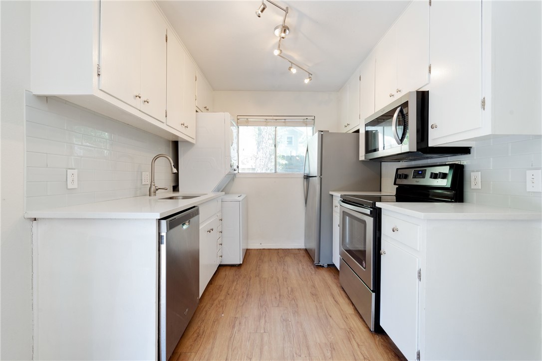 607 East 43rd Street, Unit A Austin, TX 78751 - Photo 9 of 26 a kitchen with cabinets stainless steel appliances a sink and wooden floor