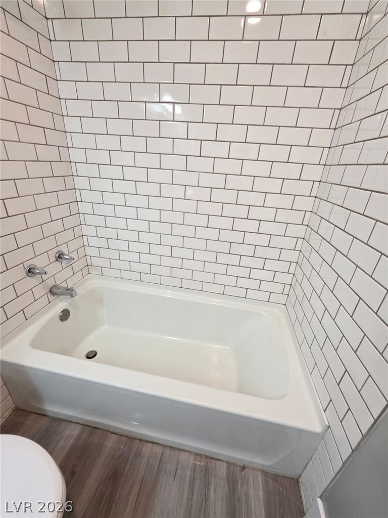 1075 East Desert Inn Road, Unit 2 Las Vegas, NV 89109 - Photo 10 of 13 Crisp subway tile surrounds a deep tub positioned over durable wood-look flooring.