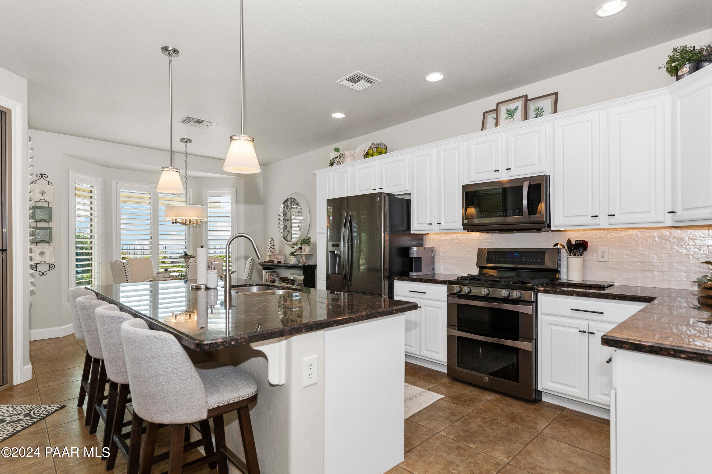 1219 Stack Rock Road Prescott Valley, AZ 86314 - Photo 8 of 41 a kitchen with stainless steel appliances granite countertop a stove top oven a sink dishwasher a dining table and chairs with wooden floor