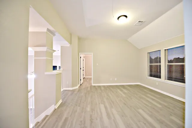 a view of a hallway with wooden floor and a bathroom