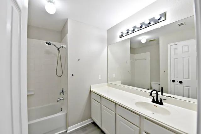 a bathroom with a double vanity sink a mirror and a bathtub