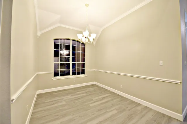 a view of an empty room with wooden floor and windows