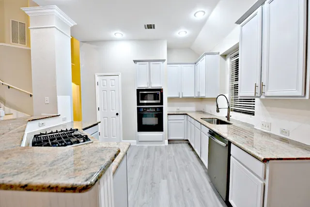 a kitchen with stainless steel appliances kitchen island granite countertop a stove a sink and a refrigerator