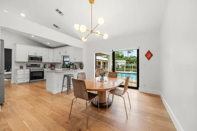 a view of a dining room with furniture a kitchen and chandelier