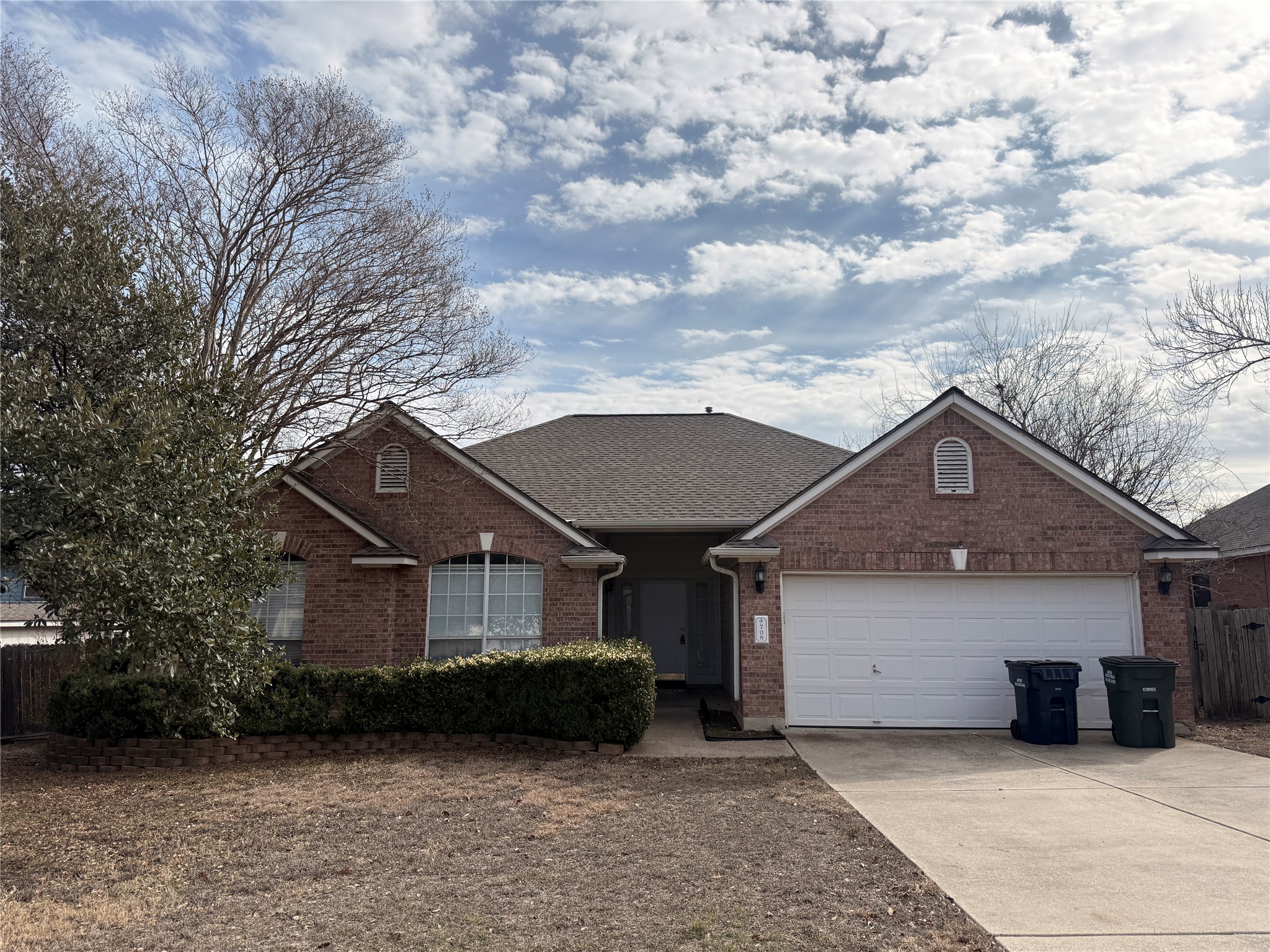 View of front of property with brick siding, concrete driveway, a shingled roof, and an attached garage