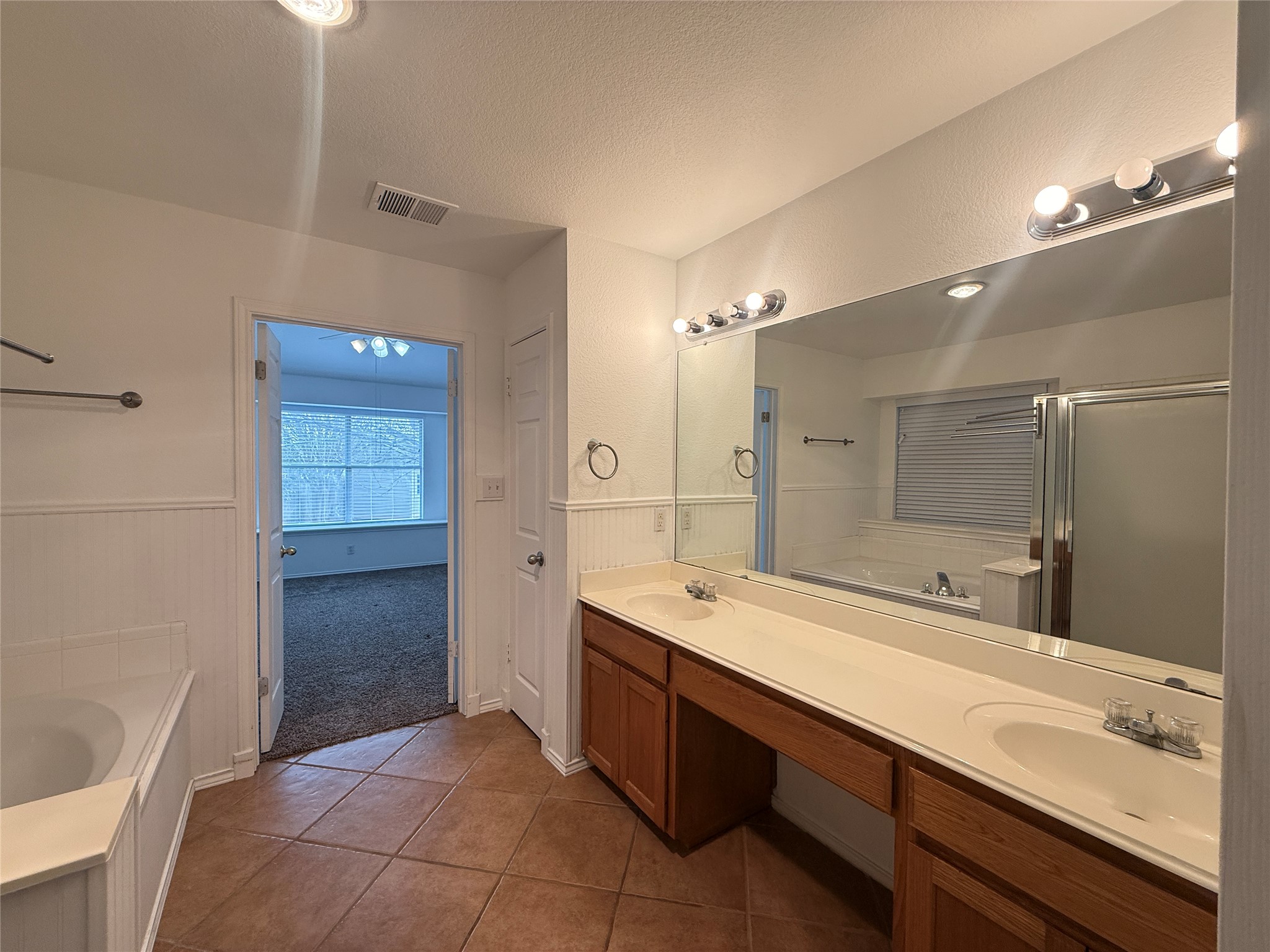 708 Spring Brook Lane Leander, TX 78641 - Photo 14 of 27 Bathroom with a garden tub, double vanity, a textured ceiling, dark tile patterned floors, and a stall shower