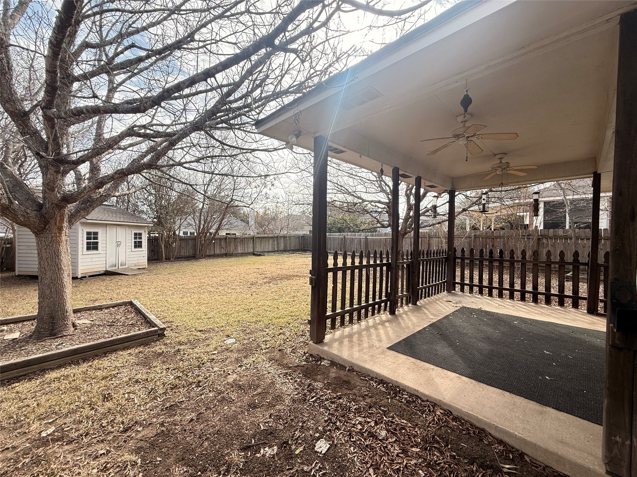 708 Spring Brook Lane Leander, TX 78641 - Photo 25 of 27 Fenced backyard featuring ceiling fan, a patio, an outdoor structure, and a vegetable garden
