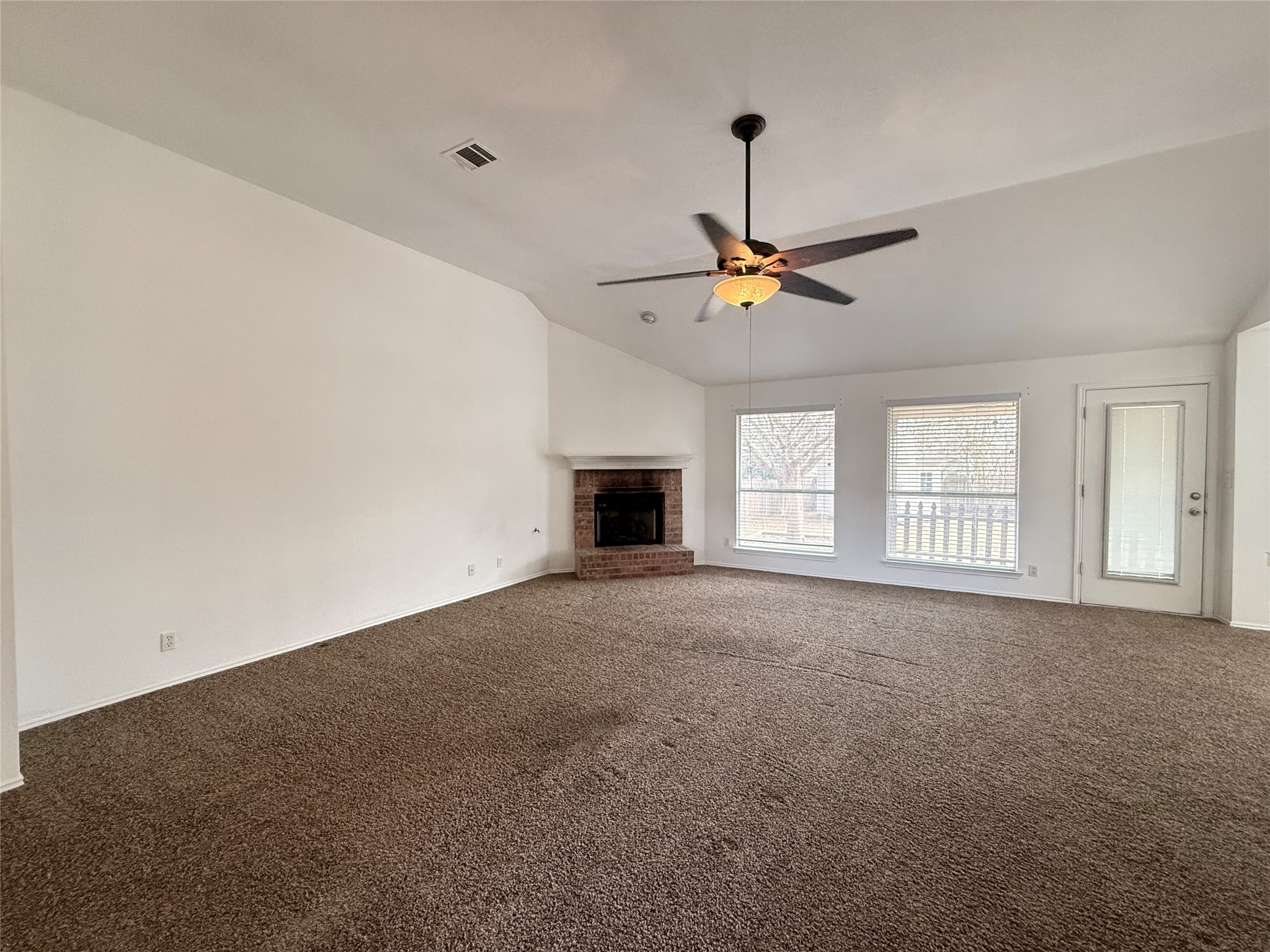 708 Spring Brook Lane Leander, TX 78641 - Photo 5 of 27 Unfurnished living room with a ceiling fan, dark colored carpet, lofted ceiling, and a fireplace