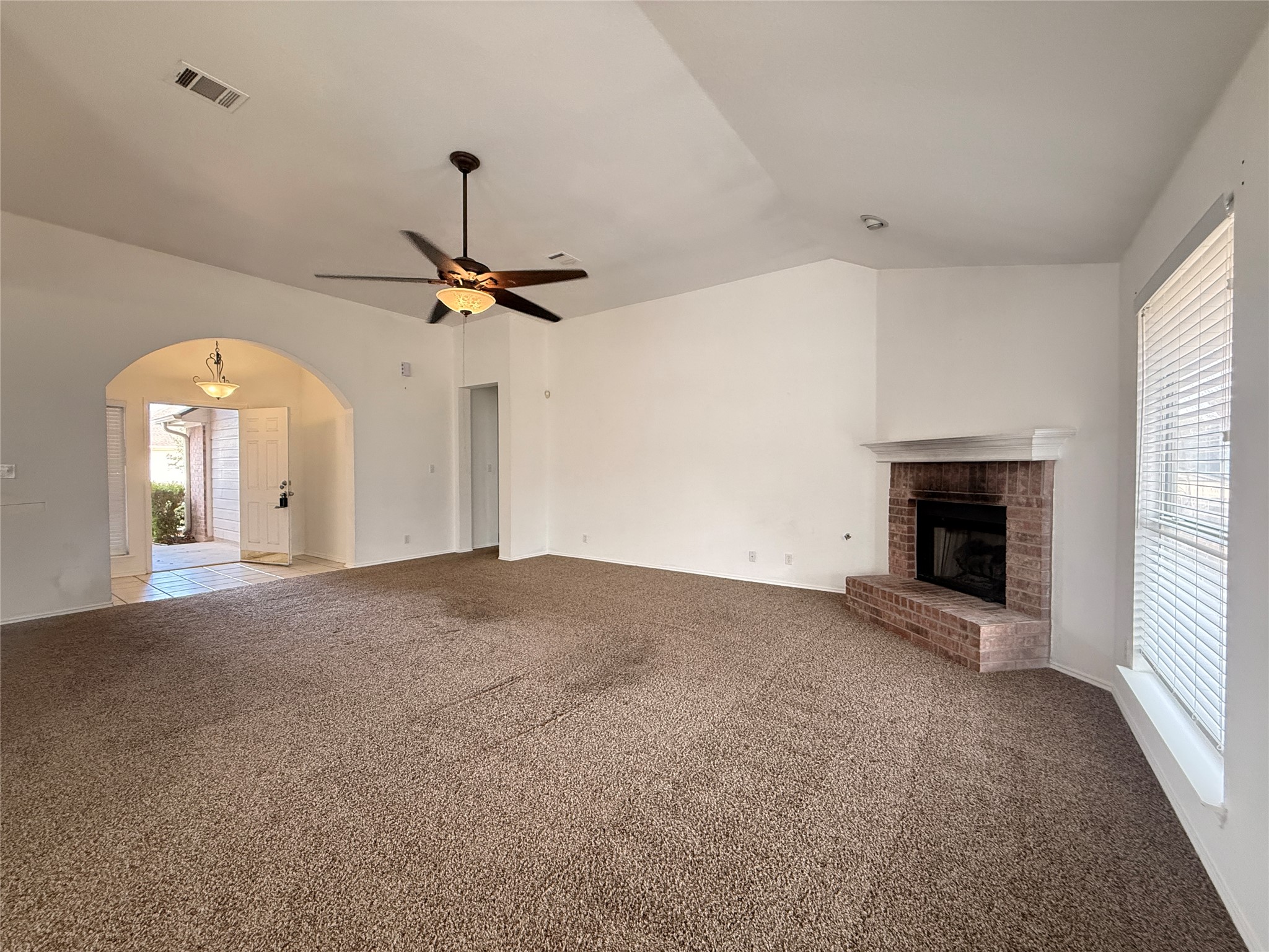 708 Spring Brook Lane Leander, TX 78641 - Photo 6 of 27 Unfurnished living room with arched walkways, ceiling fan, carpet floors, a fireplace, and vaulted ceiling