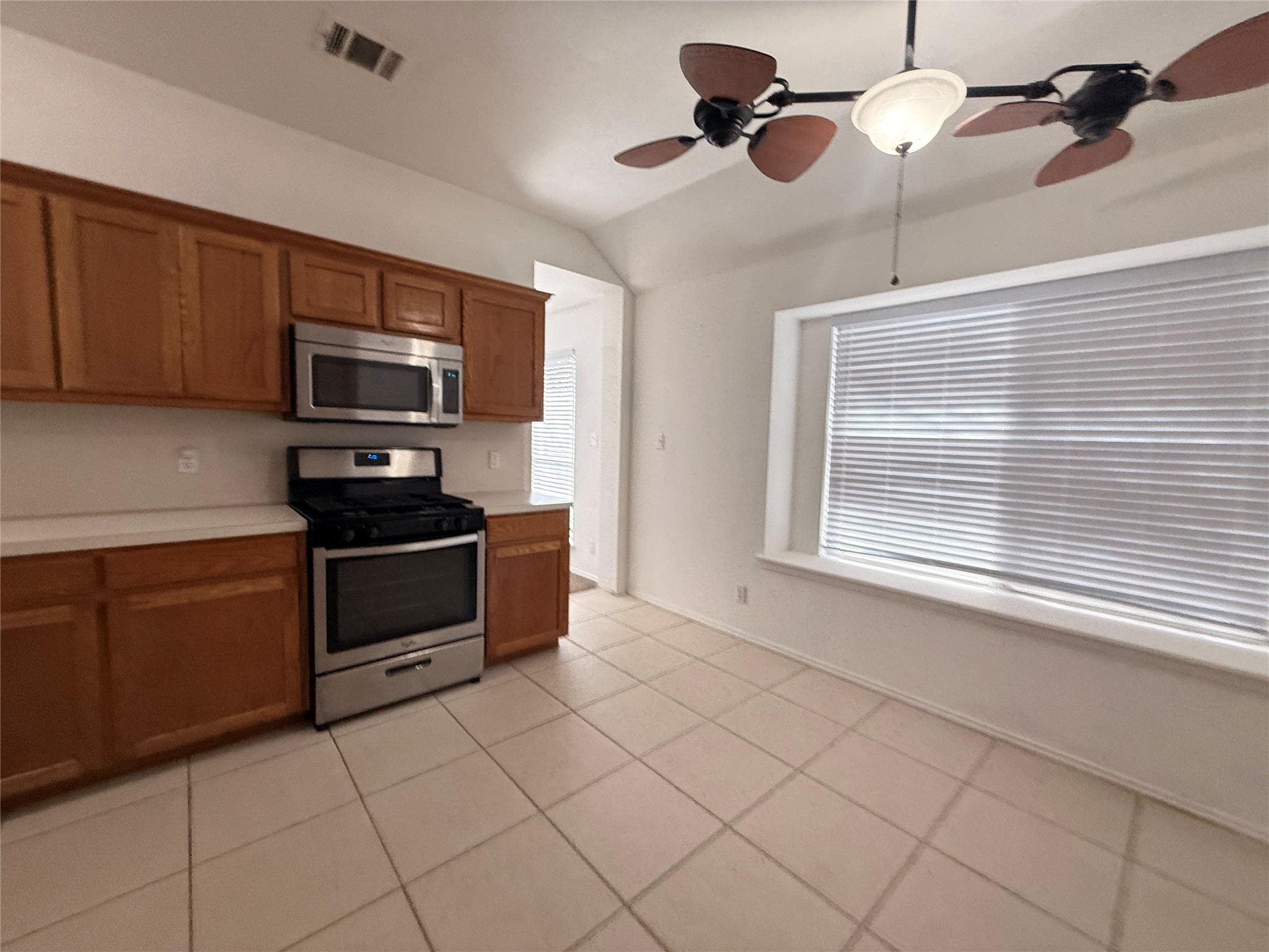 708 Spring Brook Lane Leander, TX 78641 - Photo 7 of 27 Kitchen with stainless steel appliances, wood finish cabinetry, light countertops, a ceiling fan, and vaulted ceiling