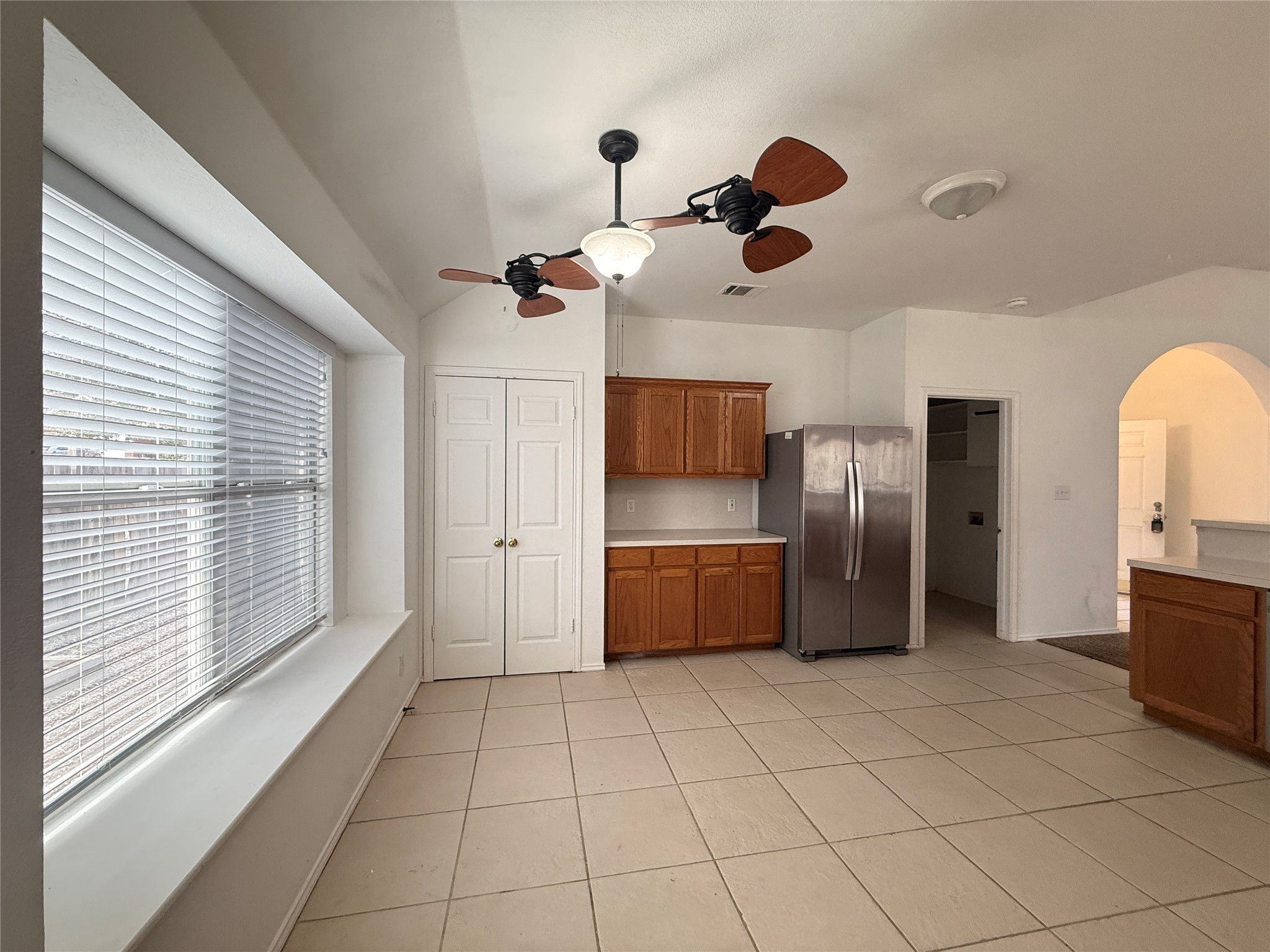 708 Spring Brook Lane Leander, TX 78641 - Photo 9 of 27 Kitchen featuring wood finish cabinetry, light countertops, freestanding refrigerator, vaulted ceiling, and arched walkways
