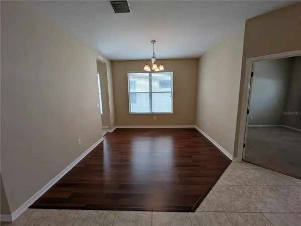 an empty room with wooden floor mirror and windows