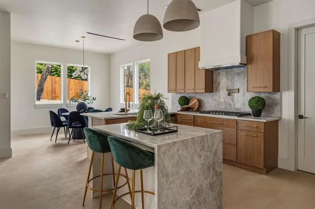 a kitchen with stainless steel appliances kitchen island granite countertop a table and chairs in it