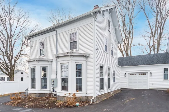 a view of a white house with a large tree