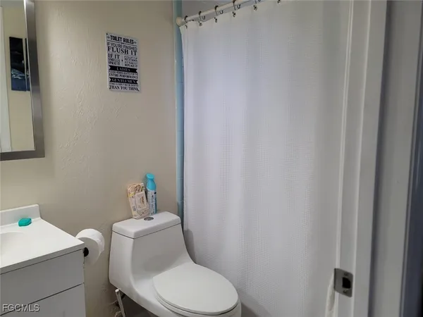 a white toilet sitting next to a white sink and vanity