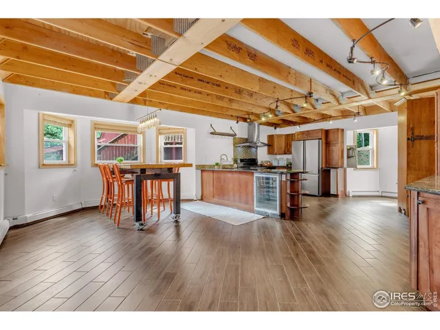 a living room with stainless steel appliances wooden floors and a view of kitchen