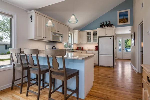 a kitchen with stainless steel appliances a dining table chairs refrigerator and sink