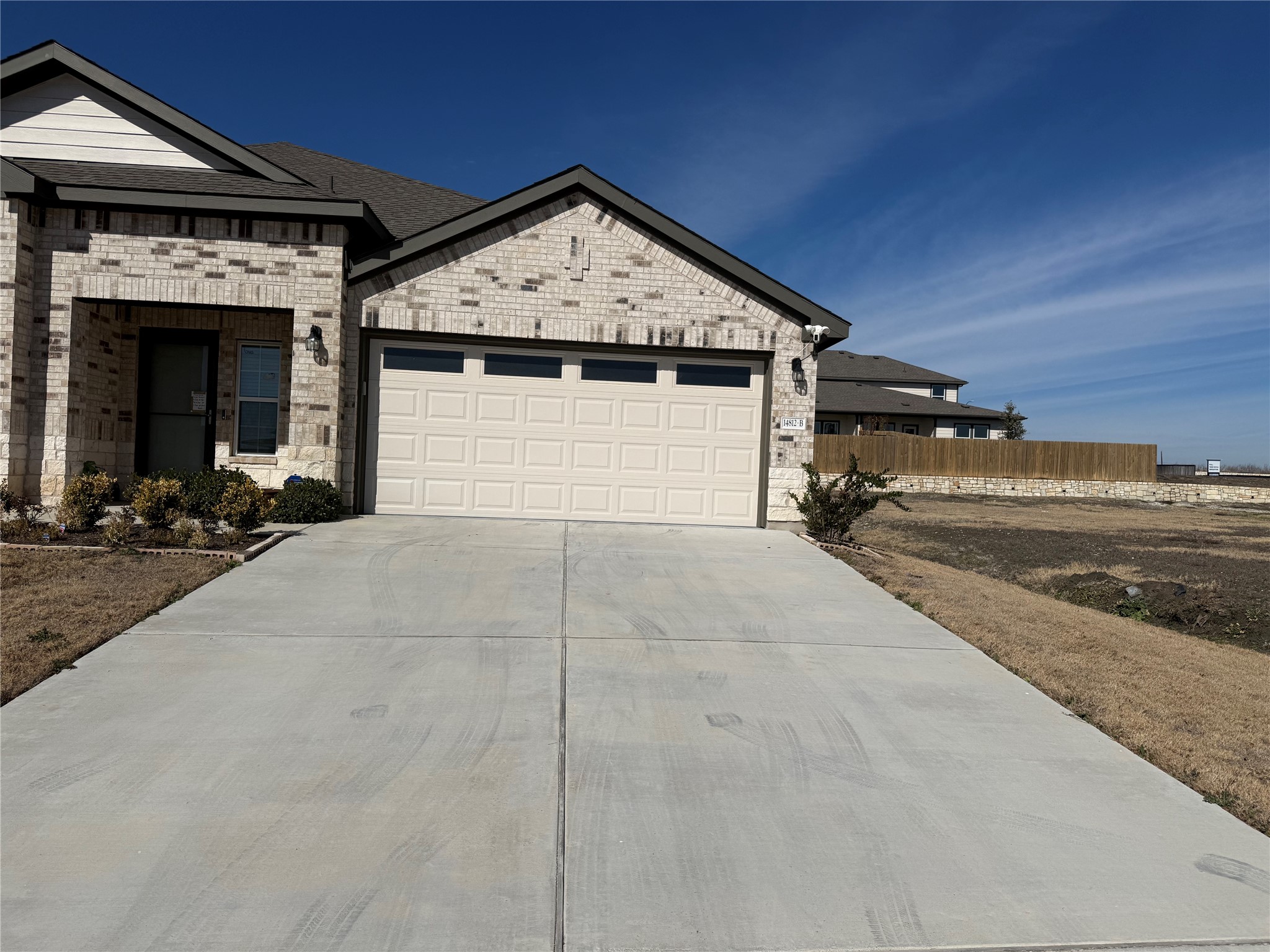 View of front of home with brick siding, concrete driveway, and an attached garage