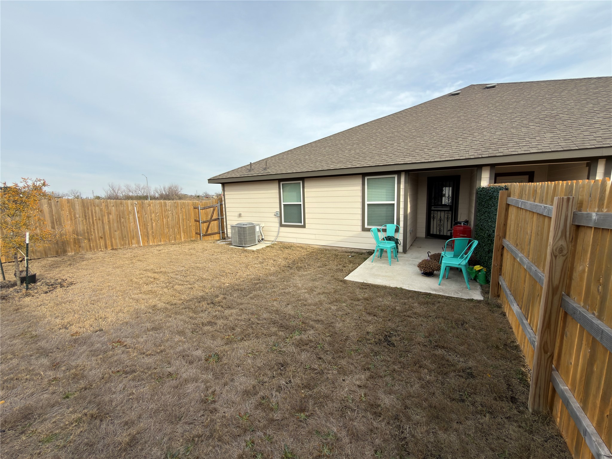14812 Perlino Way Manor, Unit B Austin, TX 78721 - Photo 11 of 11 Back of property with a patio area, a fenced backyard, a shingled roof, and an outdoor fire pit