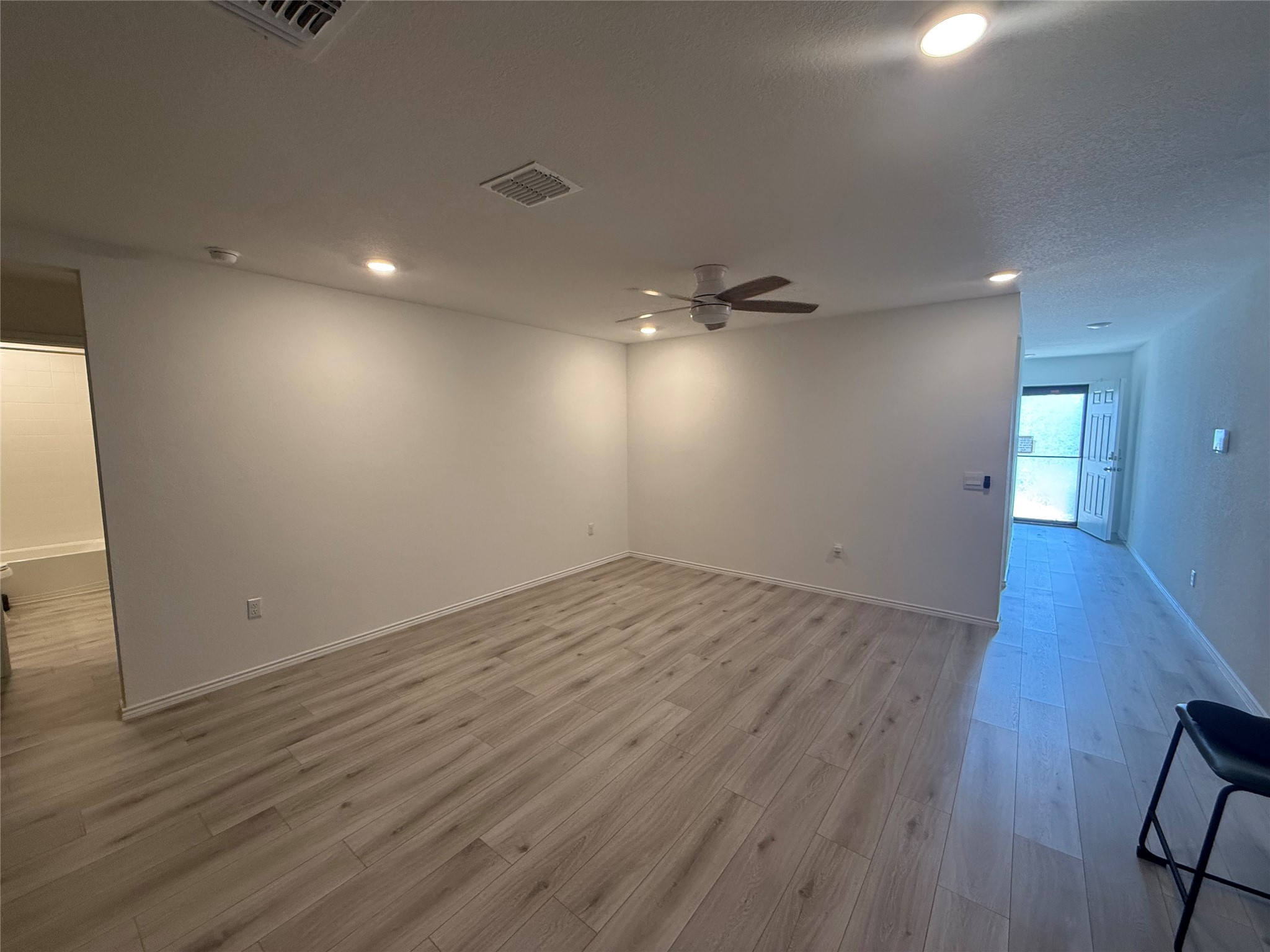 14812 Perlino Way Manor, Unit B Austin, TX 78721 - Photo 2 of 11 Unfurnished room featuring recessed lighting, light wood-type flooring, a ceiling fan, and a textured ceiling