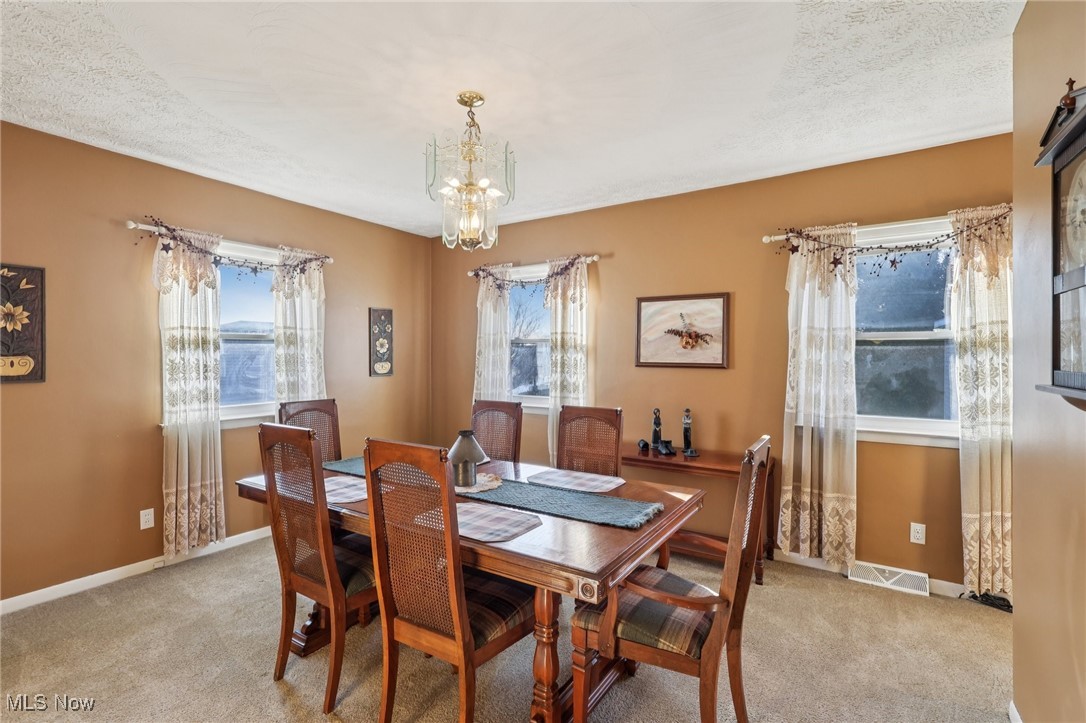 472 Stephens Road Akron, OH 44312 - Photo 15 of 46 4th bedroom currently used as a dining room with healthy amount of natural light, light colored carpet, a chandelier, and a textured ceiling