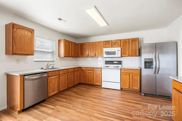 a kitchen with granite countertop wooden floors stainless steel appliances and a window