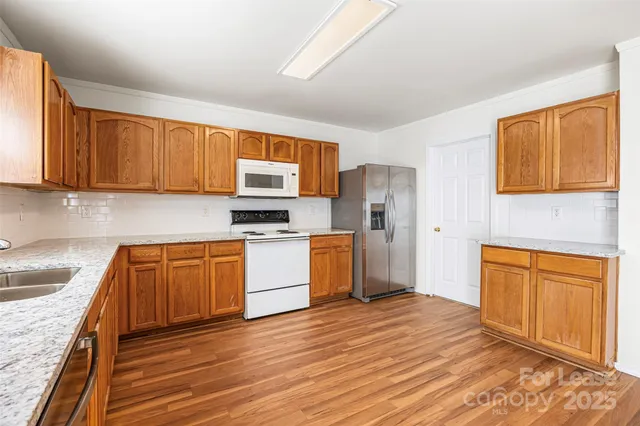 a kitchen with granite countertop wooden floors stainless steel appliances and cabinets