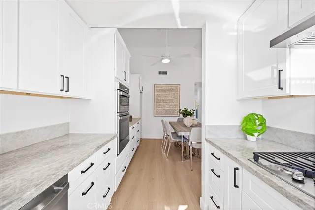 a kitchen with stainless steel appliances a stove a sink and white cabinets