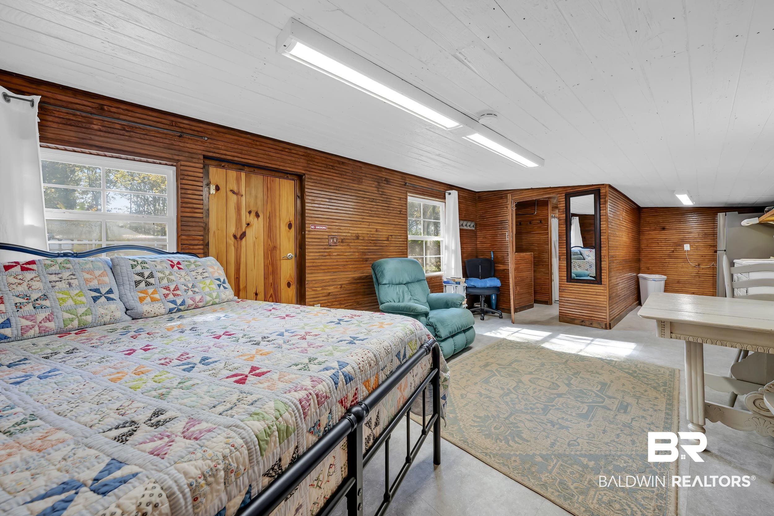 13232 Mary Ann Bch Road Fairhope, AL 36532 - Photo 45 of 79 Bedroom featuring wood walls, a desk, wooden ceiling, freestanding refrigerator, and concrete flooring