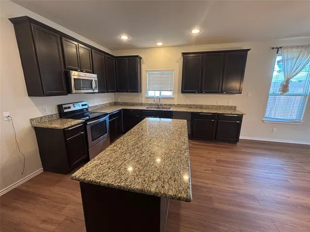 an empty room with chandelier fan and windows