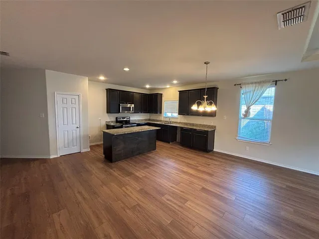 a kitchen with kitchen island granite countertop wooden cabinets and stainless steel appliances