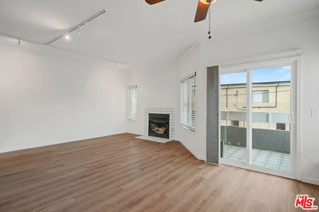 a view of an empty room with glass door and wooden floor