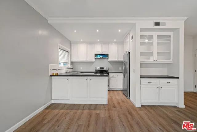 a kitchen with stainless steel appliances granite countertop a refrigerator sink and white cabinets