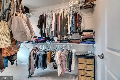 a view of walk in closet with clothes and shoes