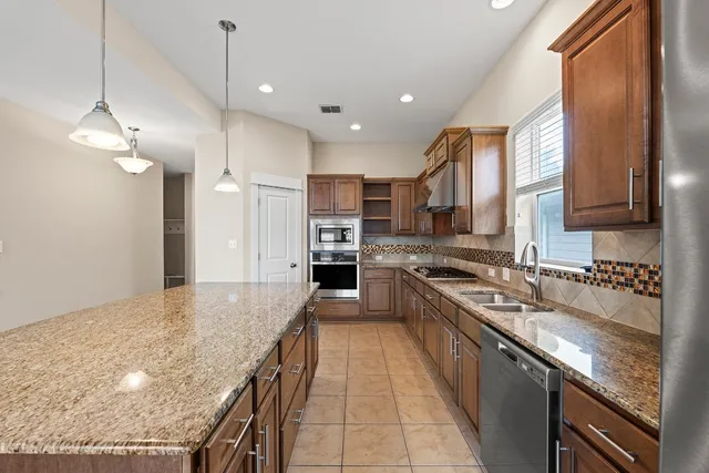 a large kitchen with stainless steel appliances granite countertop a stove a sink dishwasher and a refrigerator