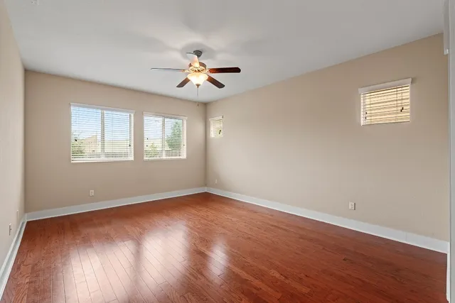 a view of an empty room with a window and wooden floor