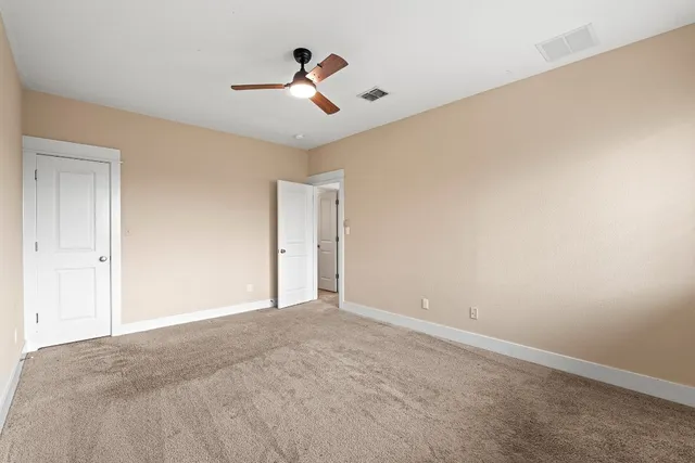 a view of an empty room and chandelier fan