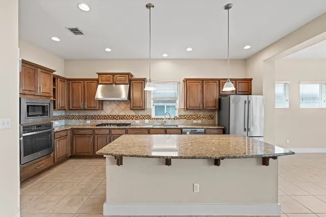 a kitchen with stainless steel appliances granite countertop a sink a stove and a refrigerator