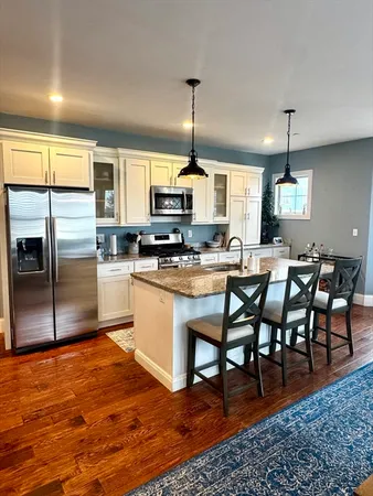 a kitchen with stainless steel appliances granite countertop a stove a sink a microwave a refrigerator and chairs