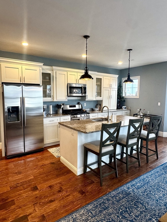 a kitchen with stainless steel appliances granite countertop a stove a sink a microwave a refrigerator and chairs