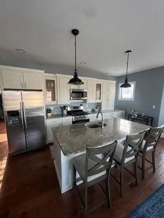 a kitchen with stainless steel appliances granite countertop a sink a stove a refrigerator cabinets and chairs