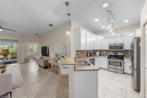 a large kitchen with kitchen island a large counter space appliances a sink and a living room view