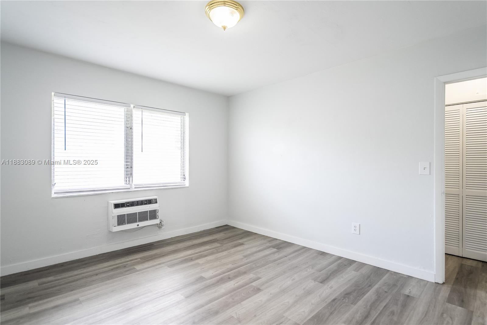 1190 71st Street, Unit 9 Miami Beach, FL 33141 - Photo 12 of 15 an empty room with wooden floor and windows
