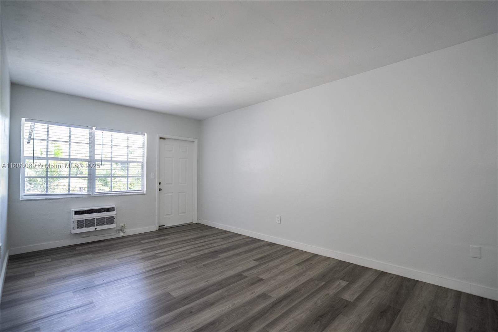 1190 71st Street, Unit 9 Miami Beach, FL 33141 - Photo 5 of 15 an empty room with wooden floor and windows