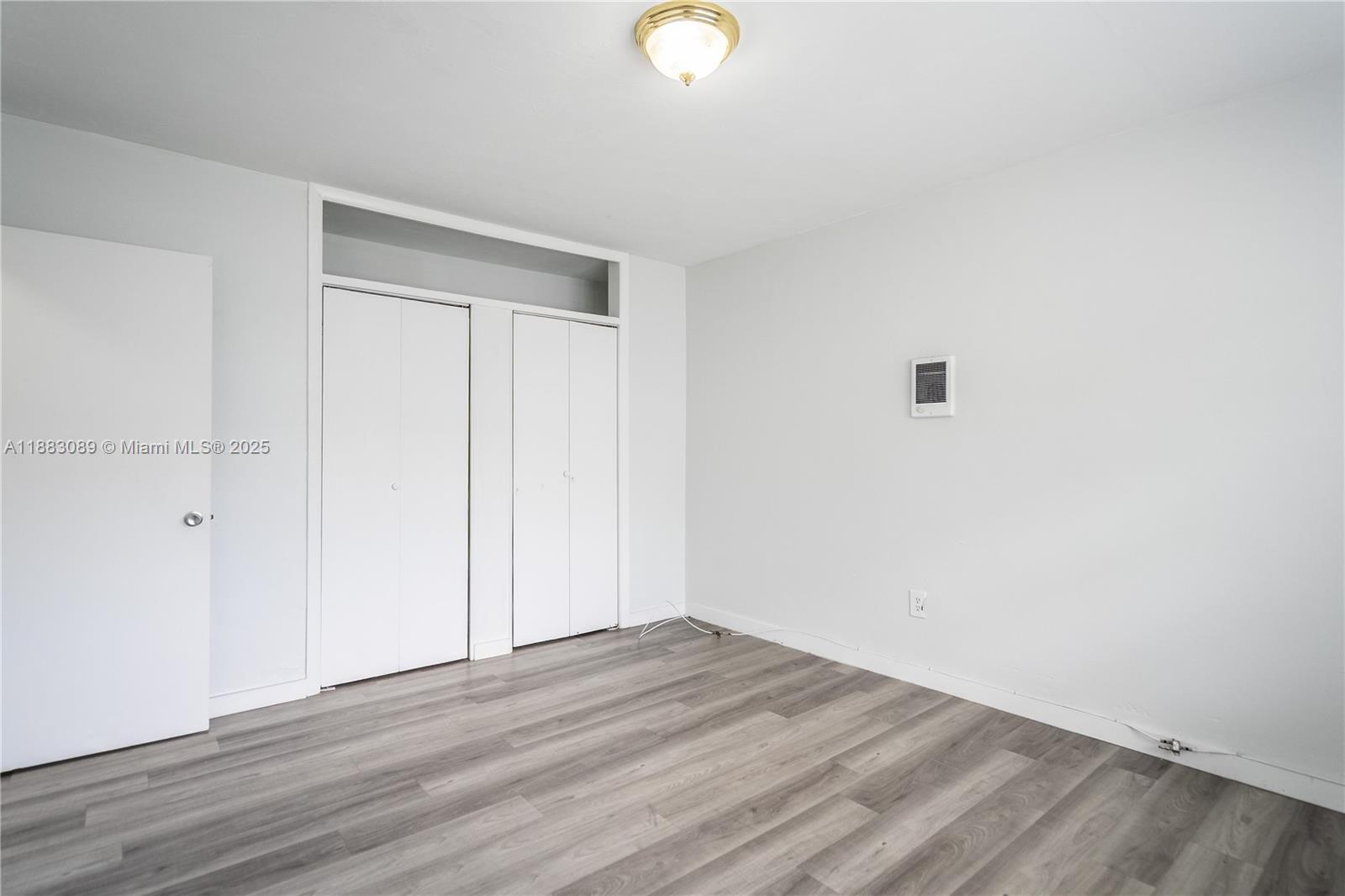 1190 71st Street, Unit 9 Miami Beach, FL 33141 - Photo 10 of 15 a view of an empty room with wooden floor and a window