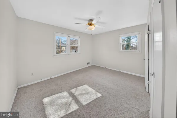 an empty room with windows and ceiling fan