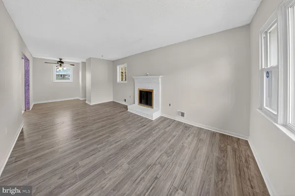 an empty room with wooden floor fireplace and windows