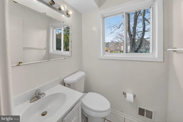 a bathroom with a toilet a sink a mirror a window and vanity